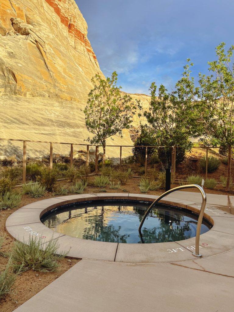 a small pool with a metal railing in front of a rock wall