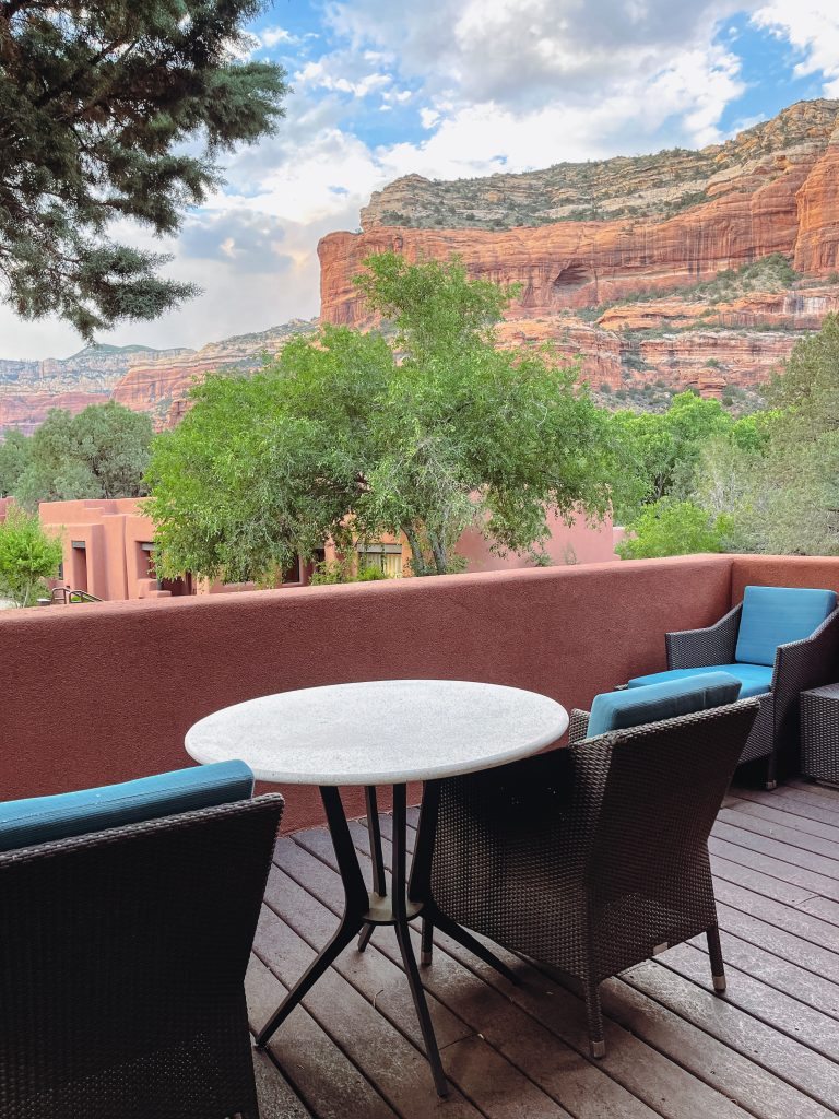 a table and chairs on a deck overlooking a red rock canyon