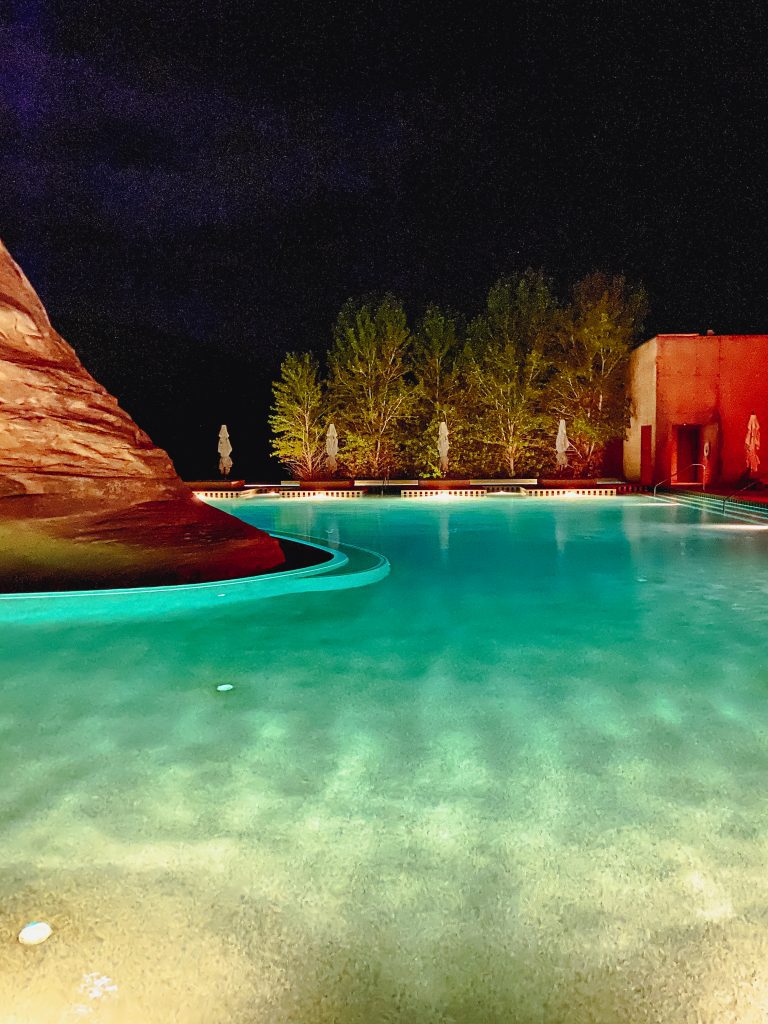 a pool with a rock and trees at night
