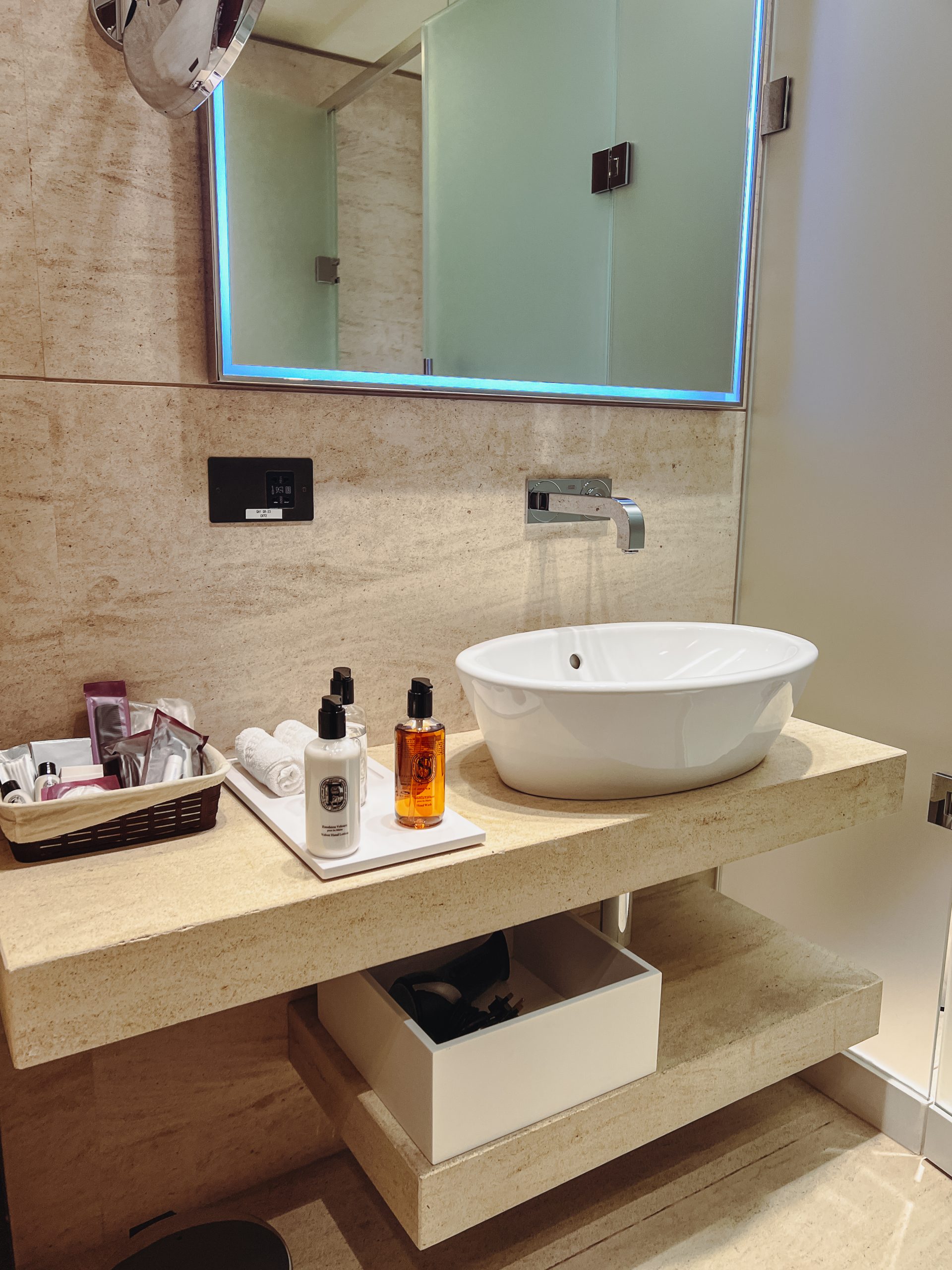 a bathroom sink with a mirror and a tray of toiletries