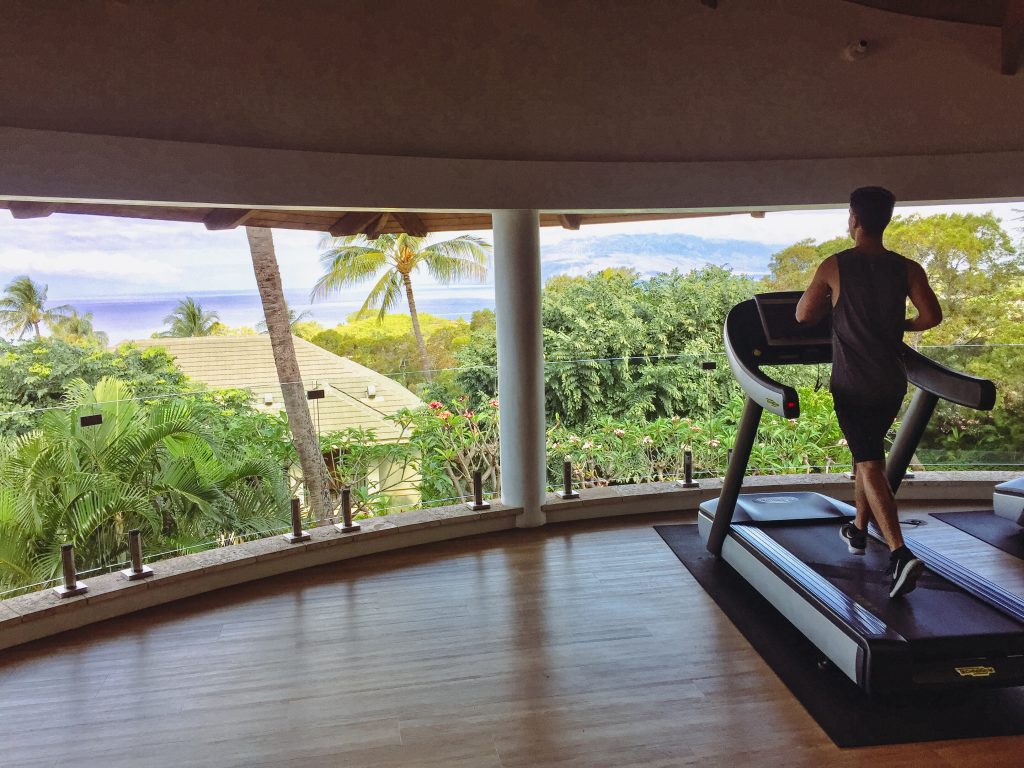 a man running on a treadmill in a room with trees and water