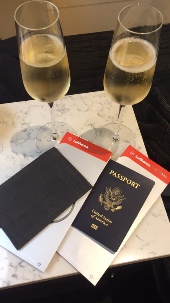 two glasses of champagne next to passport and wallet