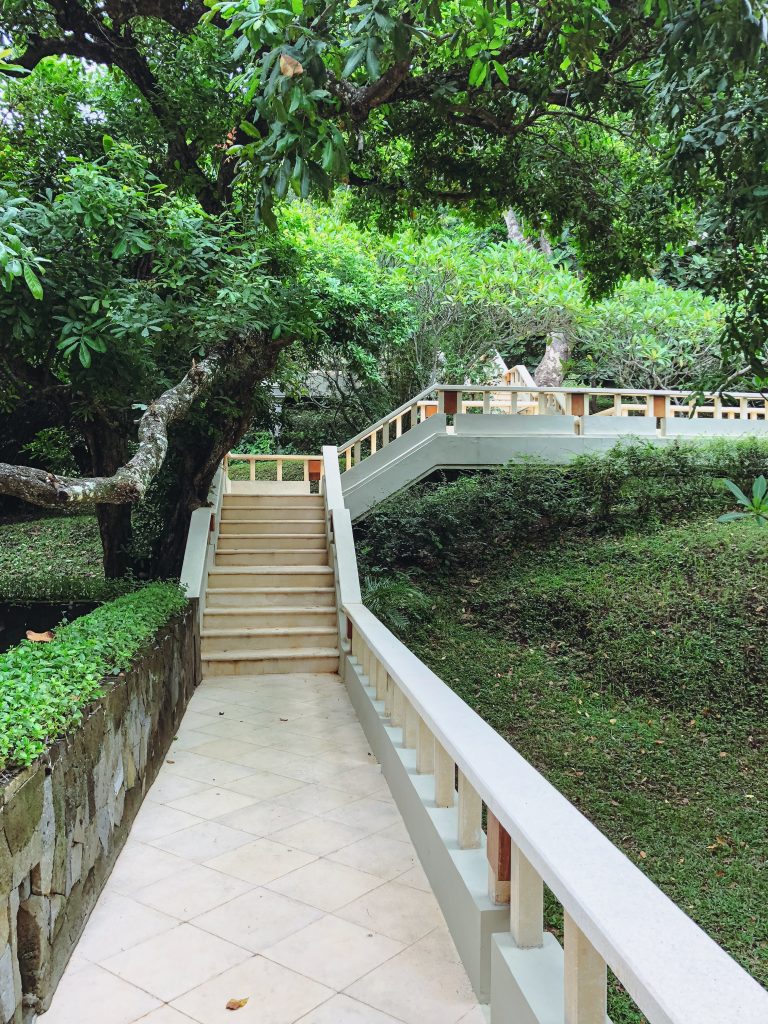 a walkway with a white railing and a stone walkway with trees