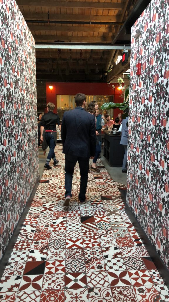 a man walking through a hallway with patterned walls