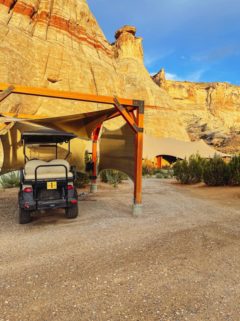 a golf cart parked in a dirt area with a large rock formation