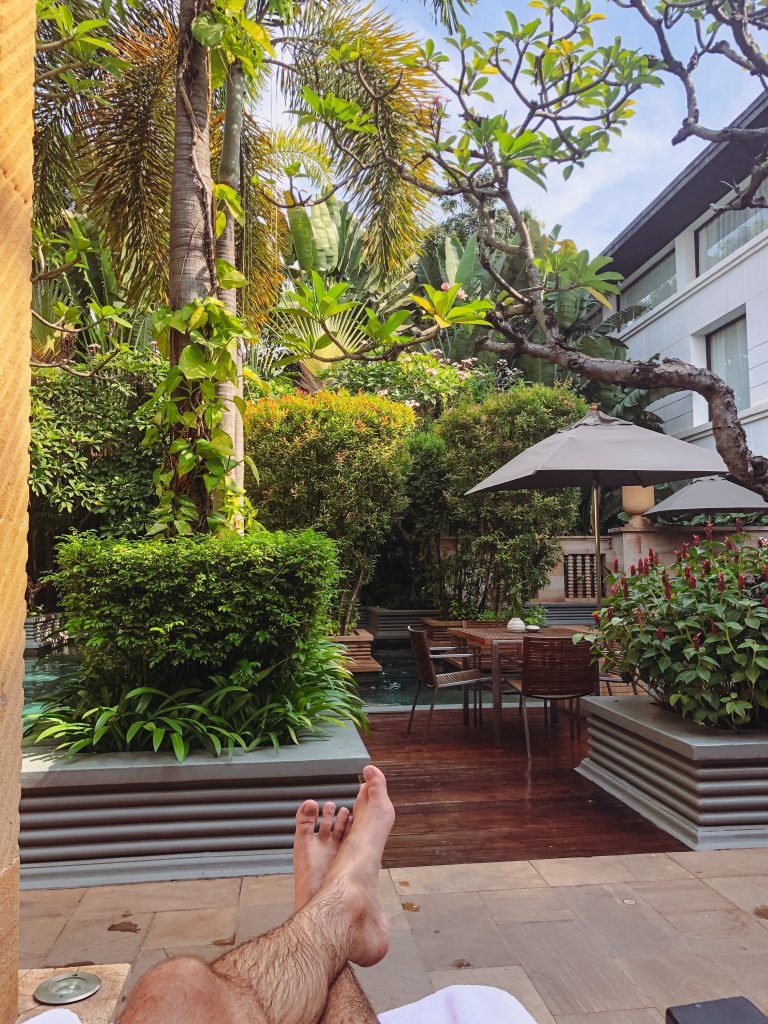 a person's feet on a patio with plants and trees