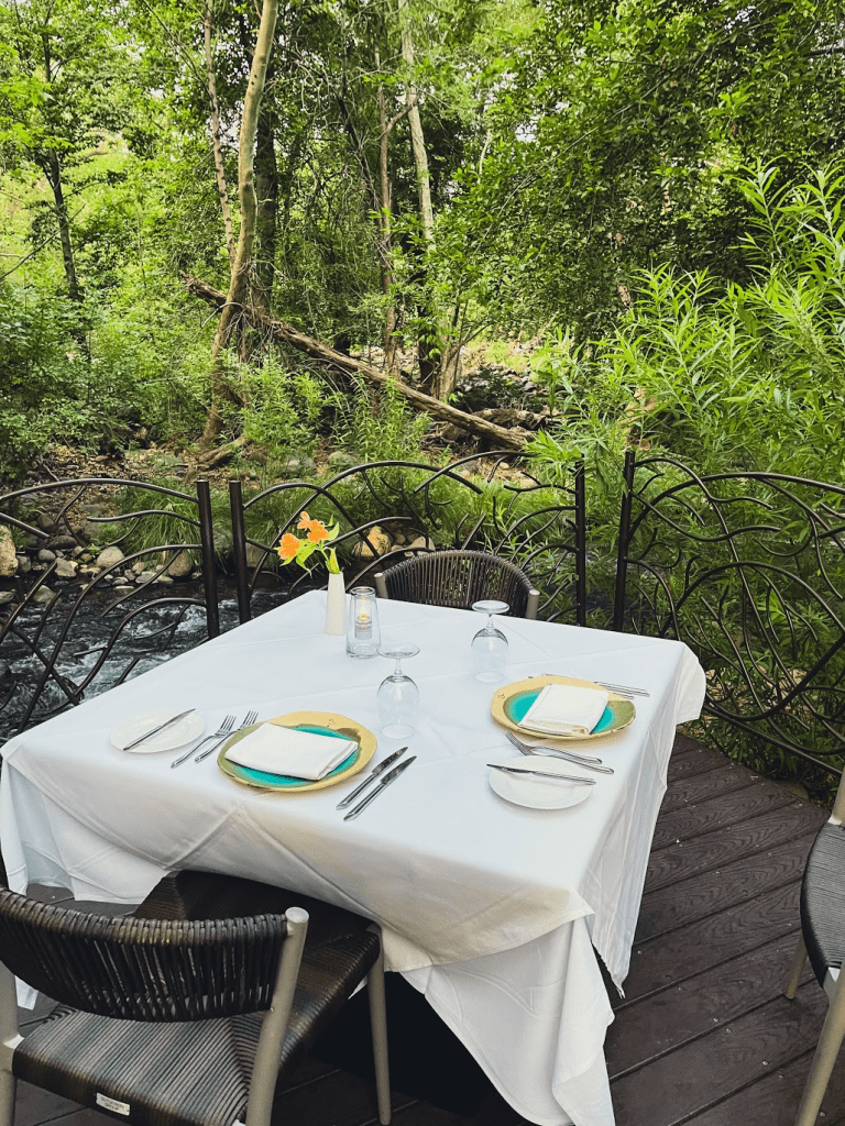 a table set up on a deck with a river in the background