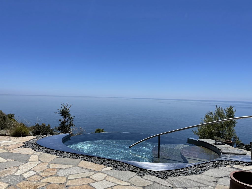 a pool with a railing overlooking the ocean