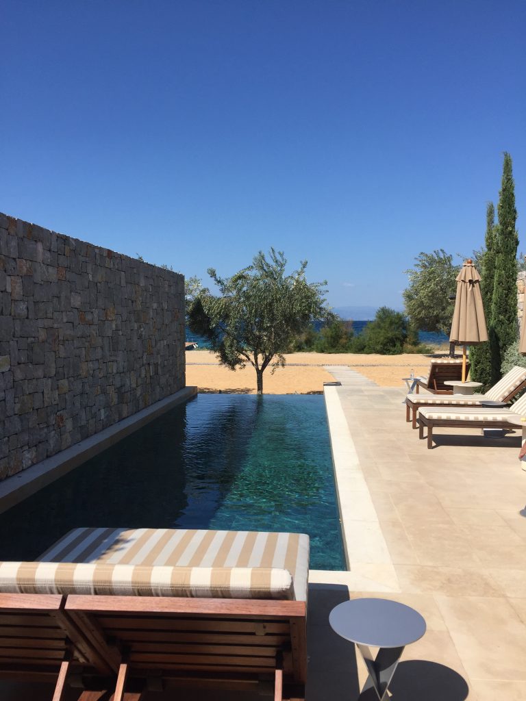 a pool with lounge chairs and a stone wall