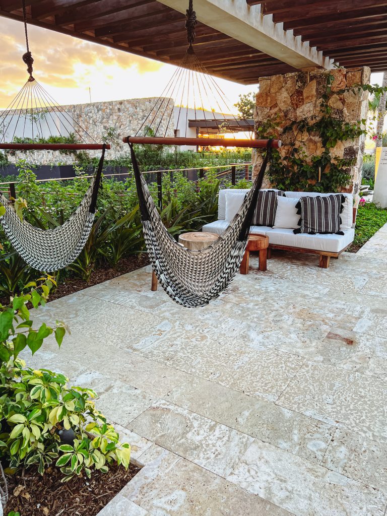 hammocks on a patio with a stone pillar and plants