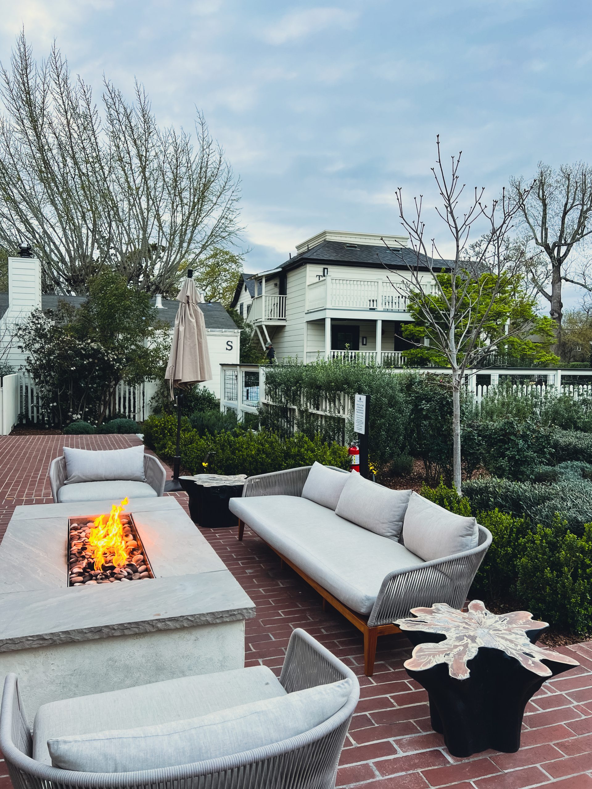 a fire pit with a couch and a couple of white houses in the background