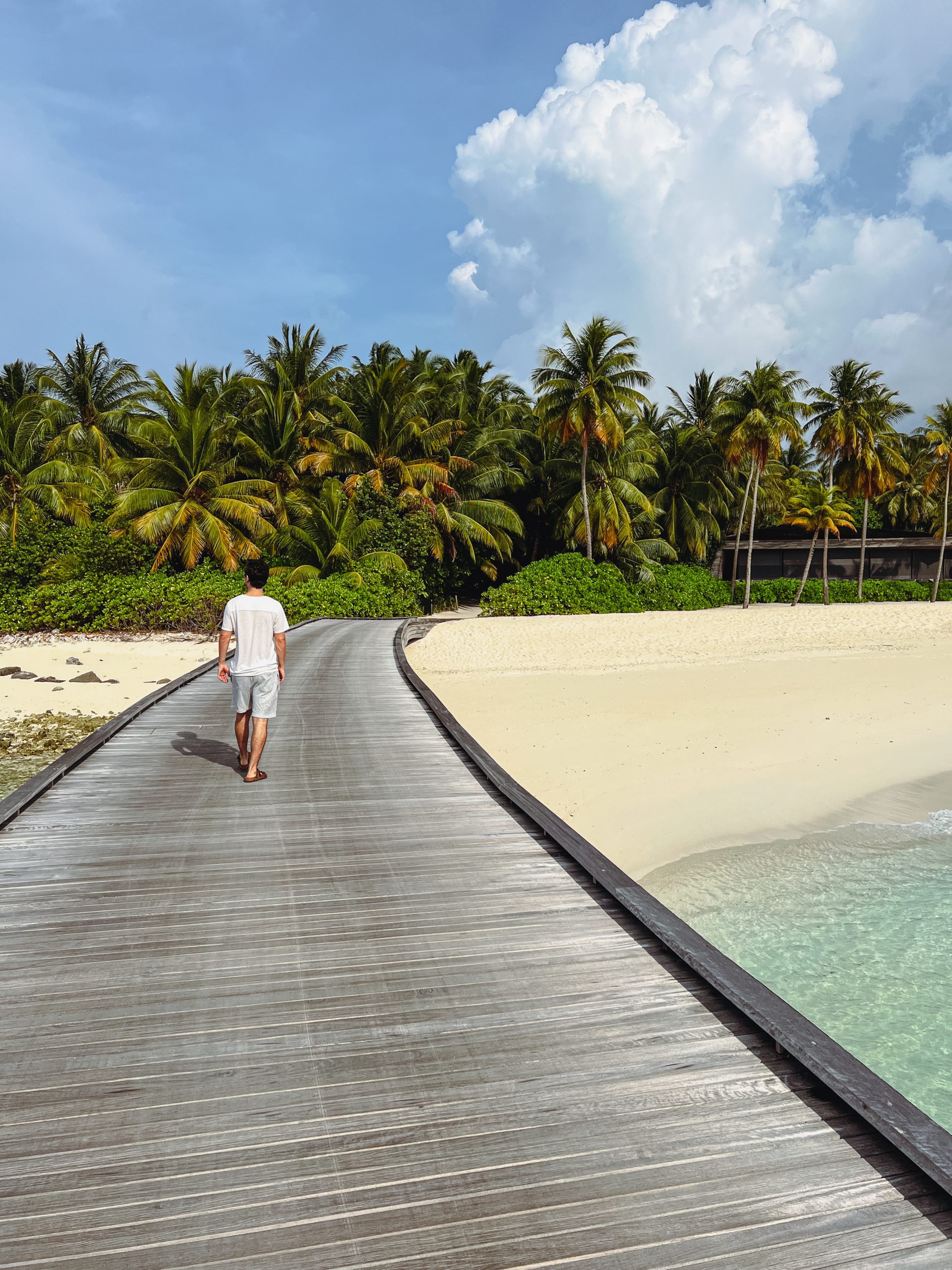 a man walking on a boardwalk on a beach
