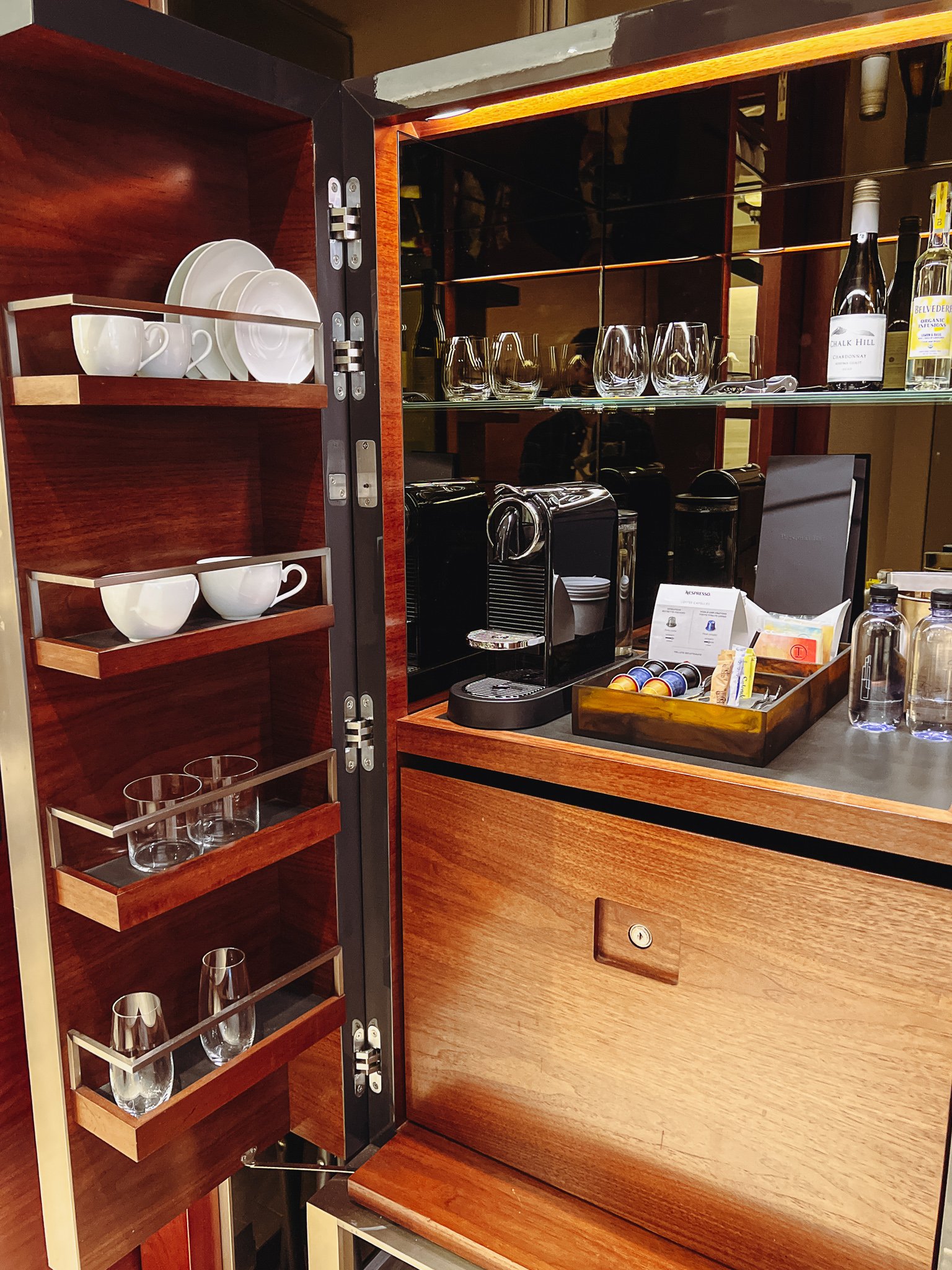 a kitchen cabinet with a counter and shelves with cups and coffee