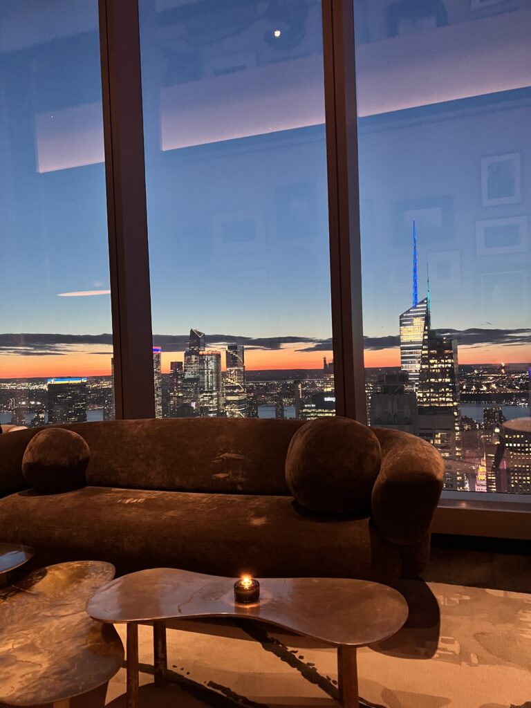 a couch and coffee tables in a room with a view of a city