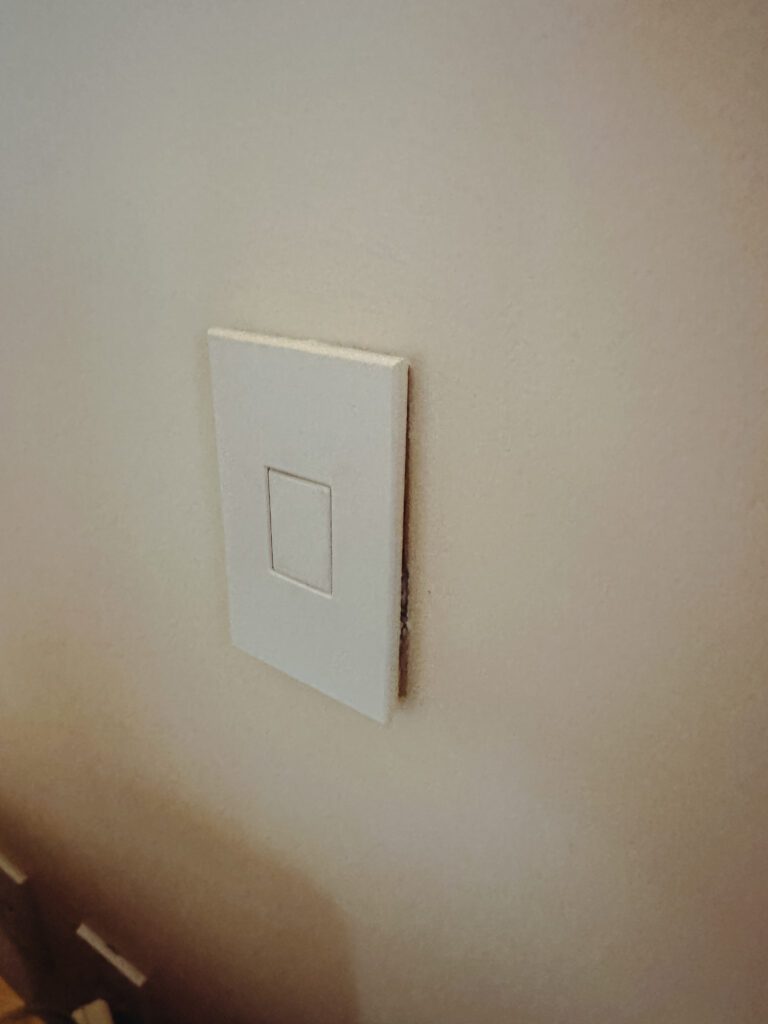 a white rectangular light switch on a wall