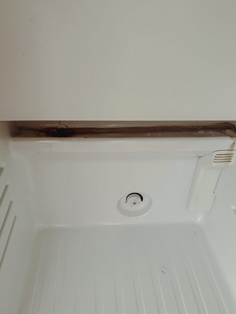 a white refrigerator with a hole in the bottom