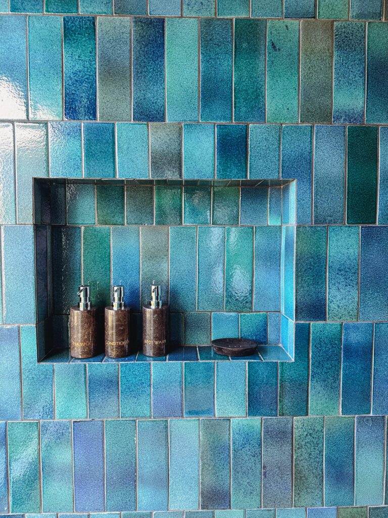 a blue tile wall with a shelf