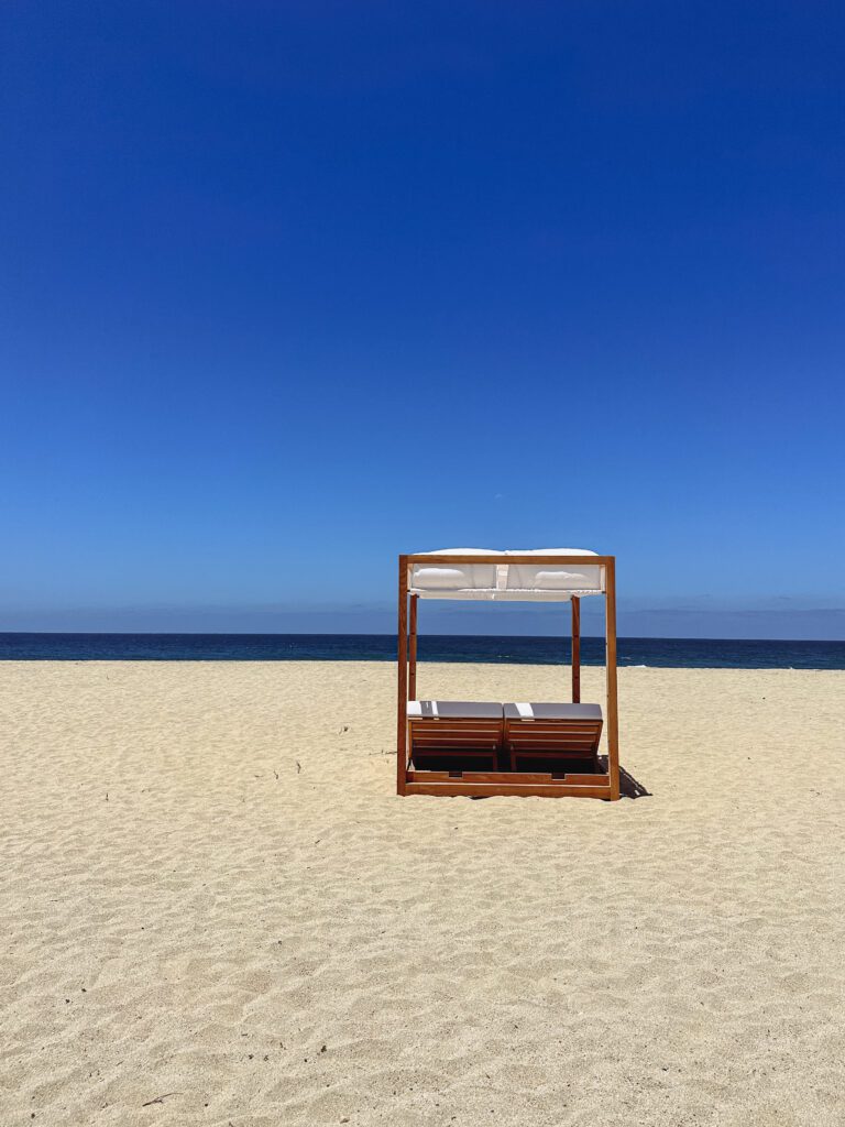 a beach with a chair and a canopy