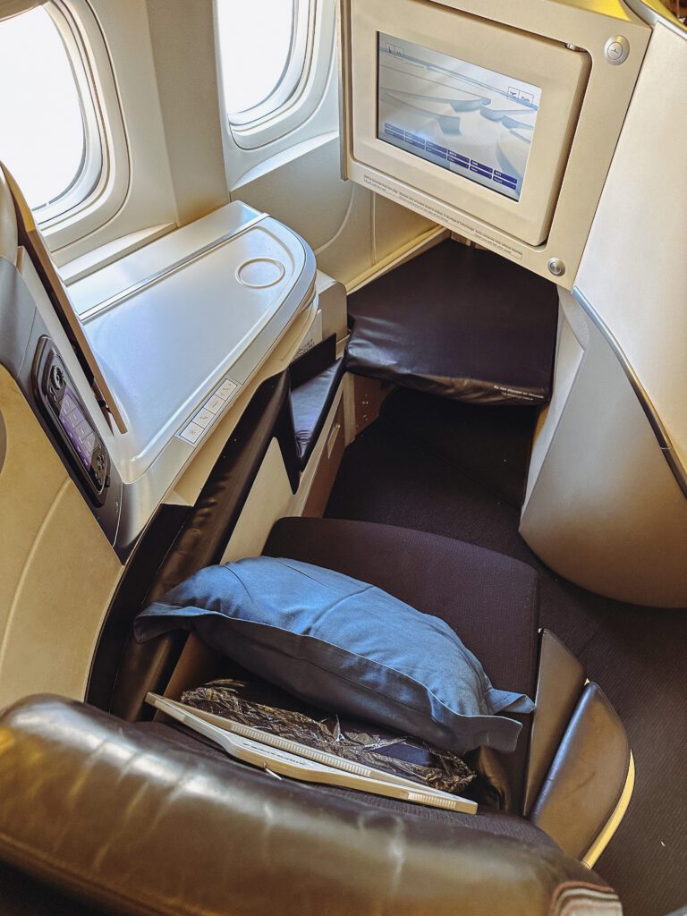 a seat with a monitor and pillows in the middle of the seat
